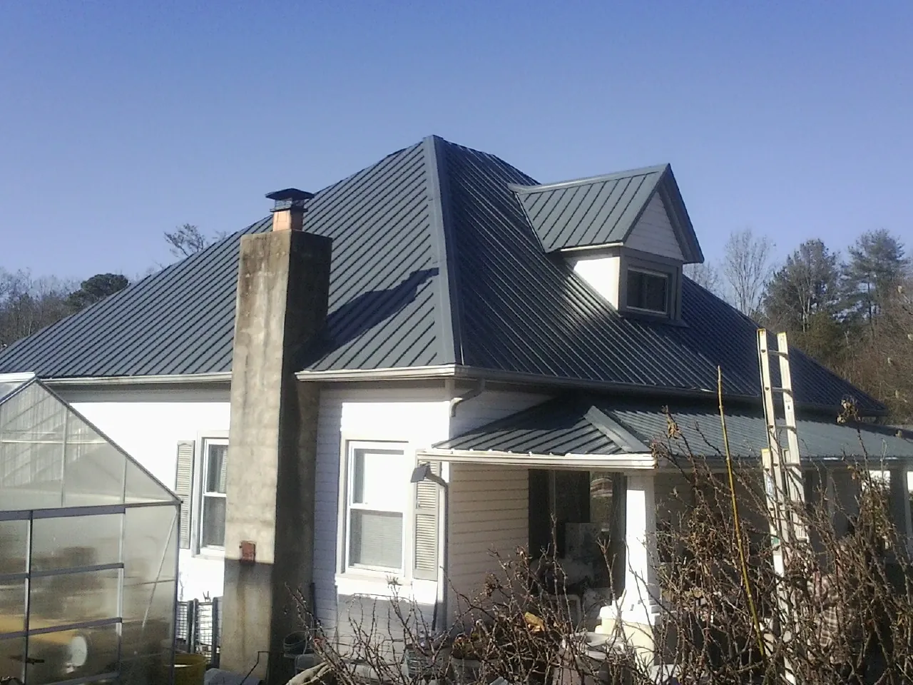 Dark blue standing seam metal roof on a white farmhouse with dormer — Slate & Tile Roof Repair by Roofing Brothers in Viola